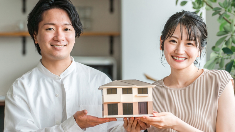家のミニチュアを持つ男女の写真